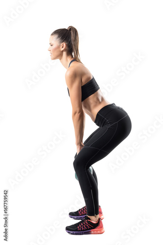 Side view of strong fitness gym girl swinging kettlebell in lower position. Full body length portrait isolated on white studio background
