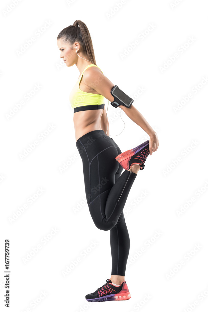Profile of athletic woman doing leg stretching quadriceps exercise