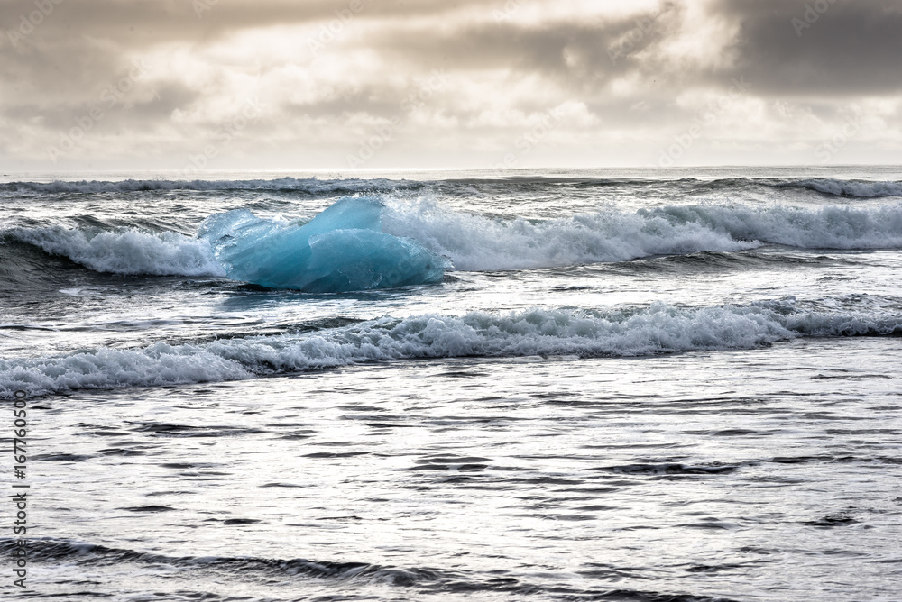 Fototapeta premium Angeschwemmter Eisberg in den Wellen am Black Diamond Beach in Südisland