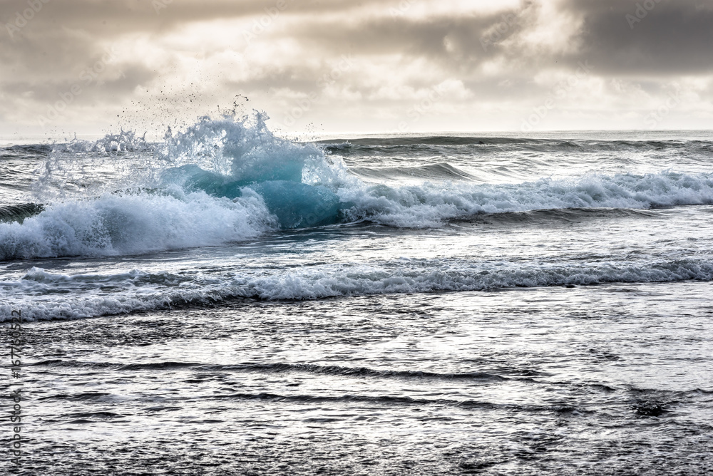 Fototapeta premium Angeschwemmter Eisberg in den Wellen am Black Diamond Beach in Südisland