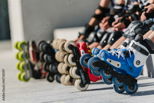 Feet of rollerbladers wearing inline roller skates sitting in outdoor skate park, Close up view of wheels befor skating
