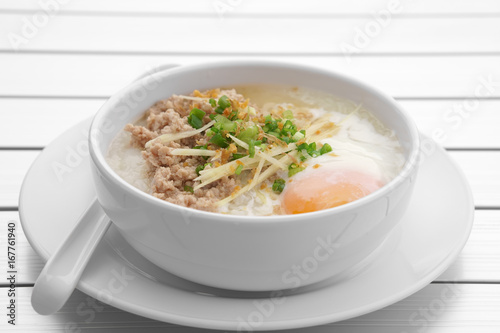 pork chops rice porridge or congee with soft boiled egg and vegetable in the white bowl with spoon on the aluminium table for delicious breakfast and clean food in the morning photo