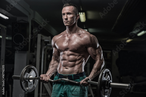 strong and handsome young man doing exercise with dumbbells