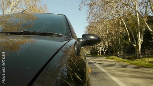 Driving a car, windshield reflection. Hood side reference. Mounted camera, front view. Black car ride. Country road, trees on the side, blue sky, day. Real Time Speed. HD. Right side wheel driving UK