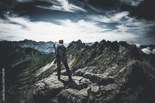 Bergsteiger steht siegreich auf dem Gipfel im Gebirge photo