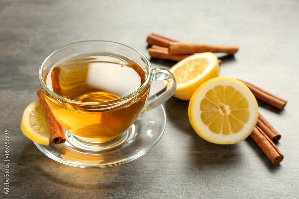 Cup with aromatic hot cinnamon tea and lemon on table