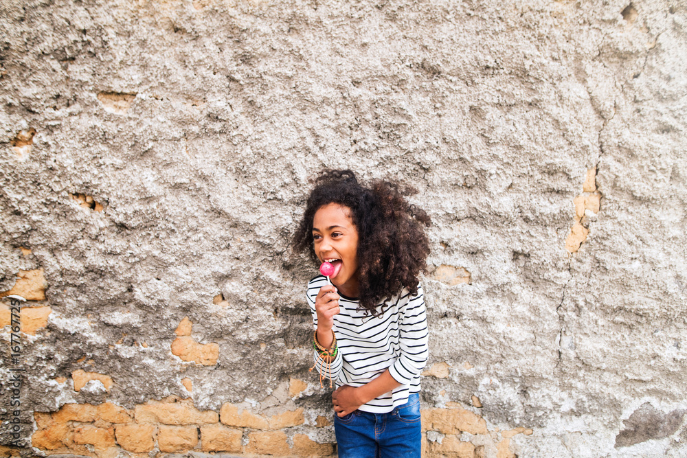 African american girl in striped t-shirt against concrete wall. African american girl in striped t-shirt against concrete wall.
