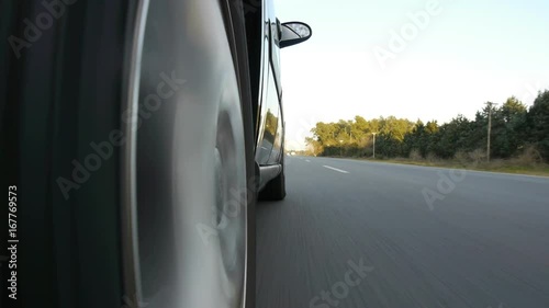 Driving a black sports / super car on a country road. Wheel spinning POV - Point of View, day country side, sunset, fall / winter. Trees on the side. Slow motion speed Right side wheel / driving UK 