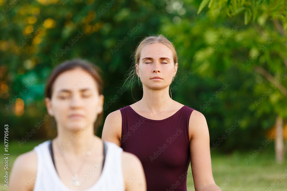 Yoga instructor doing yoga and Stretching exercise with young woman. Two person make yoga poses. Healthy lifestyle at nature with green grass Yoga instructor doing yoga and Stretching exercise with young woman. Two person make yoga poses. Healthy lifestyle at nature with green grass