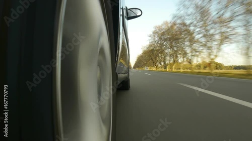 Driving a black sports / super car on a country road. Wheel spinning POV - Point of View, day country side, sunset, fall . Trees on the side. Fast Speed / time-lapse. Right side wheel / driving UK 
