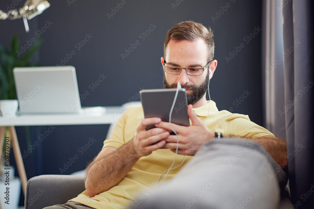 Self employ businessman using tablet device while sitting on sofa at modern home office Self employ businessman using tablet device while sitting on sofa at modern home office