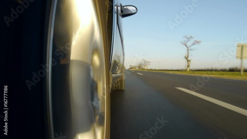 Driving a black sports / super car on a country road. Wheel spinning POV - Point of View, day country side, sunset, fall / winter. Trees on the side. Slow motion speed. Right side wheel / driving UK 