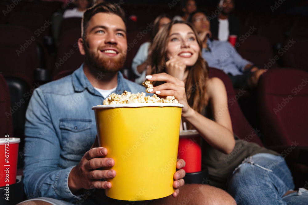 Happy smiling couple holding a big popcorn bucket