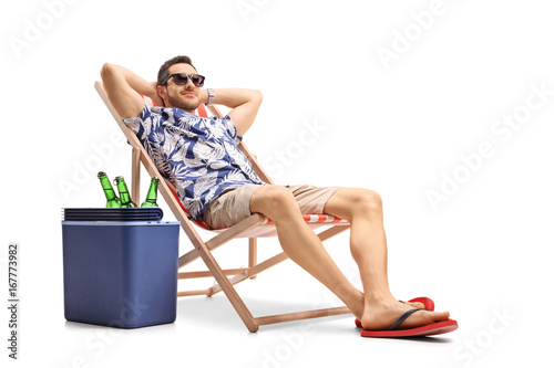 Canvas Print Tourist relaxing in a deck chair next to a cooling box