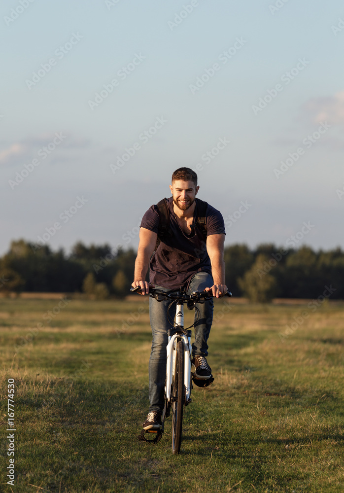 Young man Cyclist riding bike in wood at sunset Young man Cyclist riding bike in wood at sunset