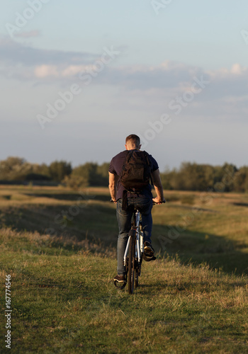 Young man Cyclist riding bike in wood at sunset