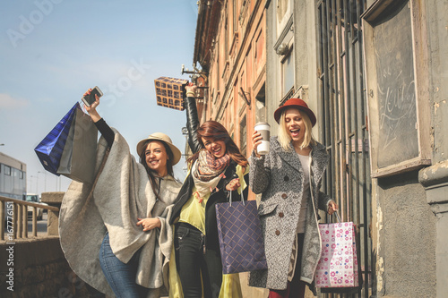 Three best friends walking on the street . Young female best friends doing shopping on the streets.