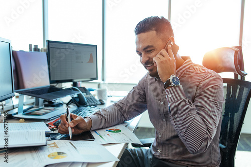 Entrepreneur discussing work over mobile phone sitting at his of