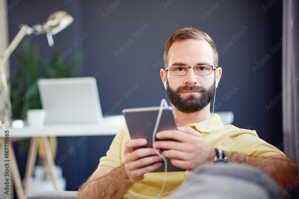 Self employ businessman using tablet device while sitting on sofa at modern home office Self employ businessman using tablet device while sitting on sofa at modern home office