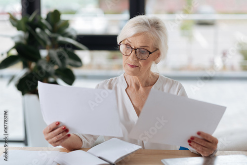 Foto Serious smart woman comparing two documents