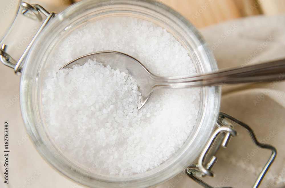 White sea salt white napkin in a jar on an iron spoon White sea salt white napkin in a jar on an iron spoon