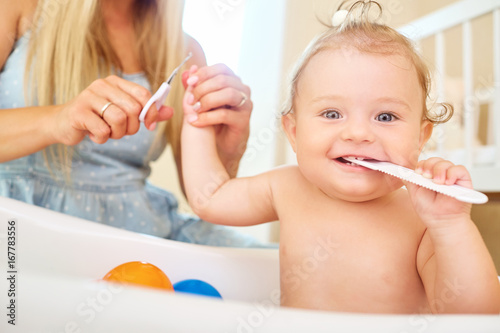 Foto Mother cutting nails with scissors to the baby