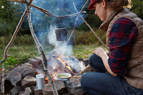 Woman sitting beside camp fire, cooking food, Colgate Lake Wild Forest, Catskill Park, New York State, USA photo