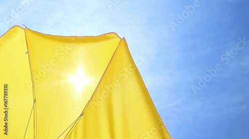 Part of a yellow parasol against the blue summer sky