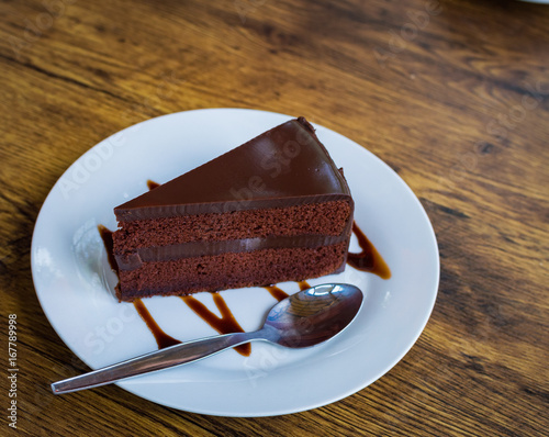 Piece of chocolate cake with spoon on white plate photo