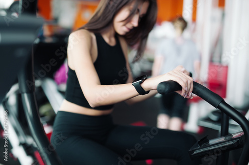 Woman 20s wearing smart watch working out on exercise bike