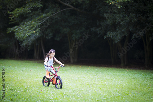 Happy little girl riding a red bicycle