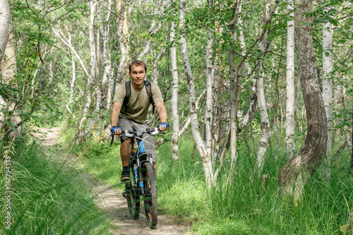 a young man rides through a forest path on a bike