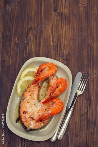 fried salmon with shrimps on white dish on wooden background
