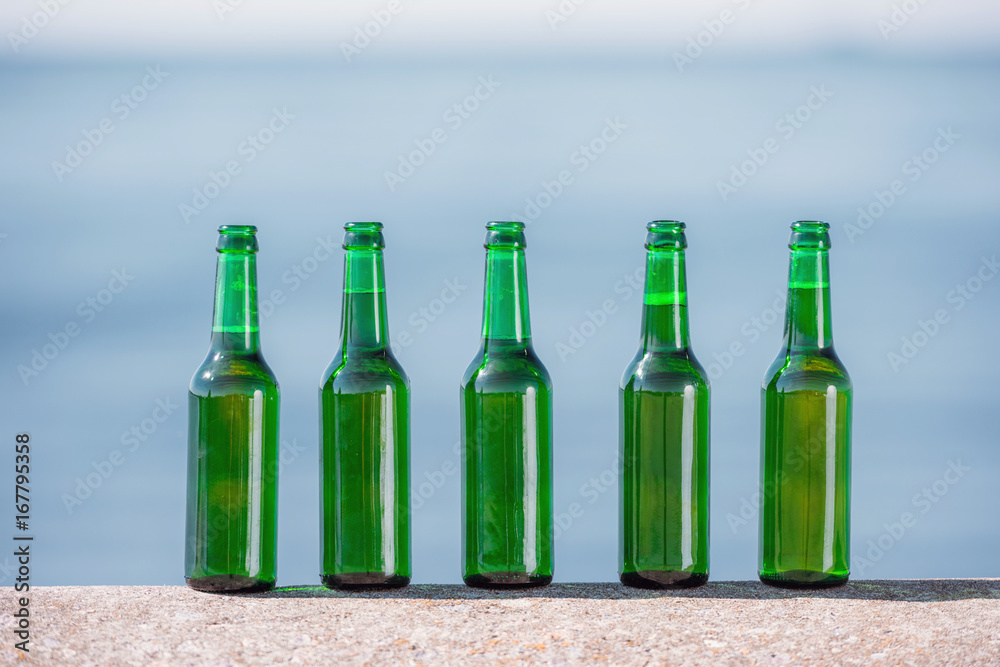 close up view of bottles of beer standing in line on parapet close up view of bottles of beer standing in line on parapet