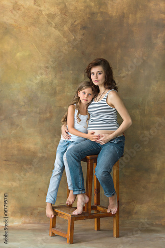 Pregnant mother with teen daughter. Family studio portrait over blue background © master1305