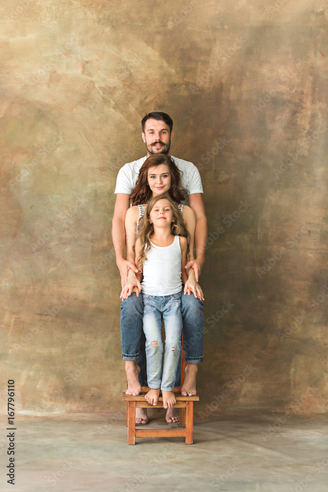 Pregnant mother with teen daughter and husband. Family studio portrait over brown background