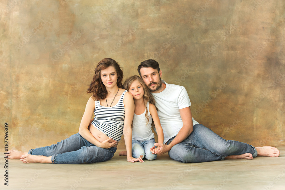 Pregnant mother with teen daughter and husband. Family studio portrait over  brown background Stock Photo | Adobe Stock
