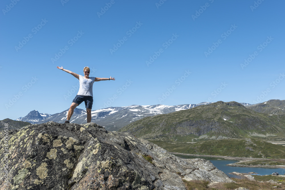 adult woman happy on a rock looking over the blue water