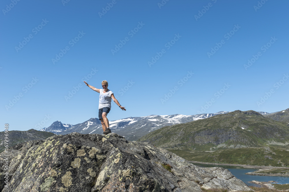 adult woman happy on a rock looking over the blue water