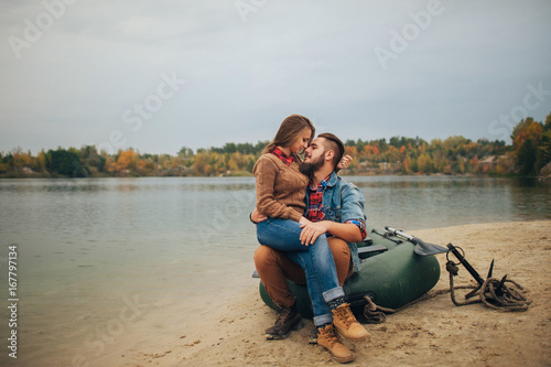 Young couple in love, boat ride on the river, next to the forest.