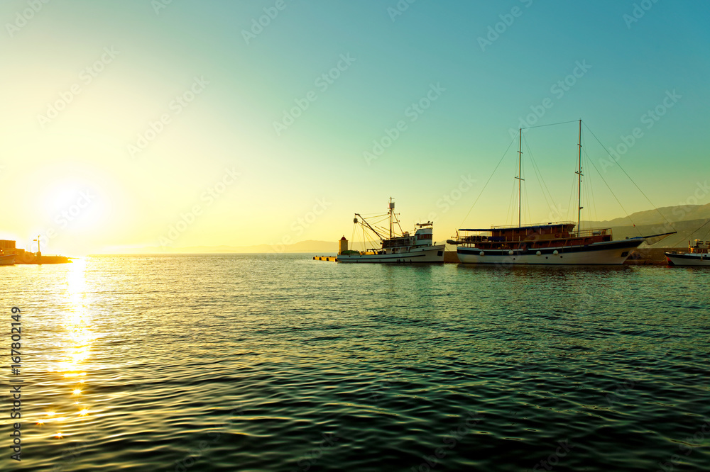 Fishing trawler and a sailboat moored in the harbor of a small town Postira - Croatia, island Brac