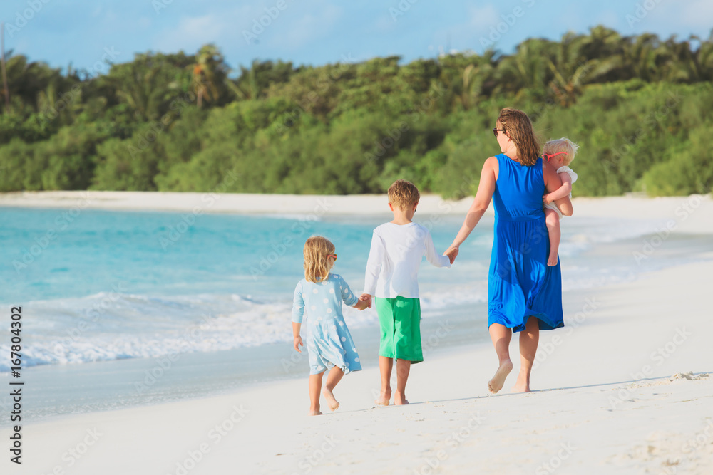 mother with three kids walk on beach