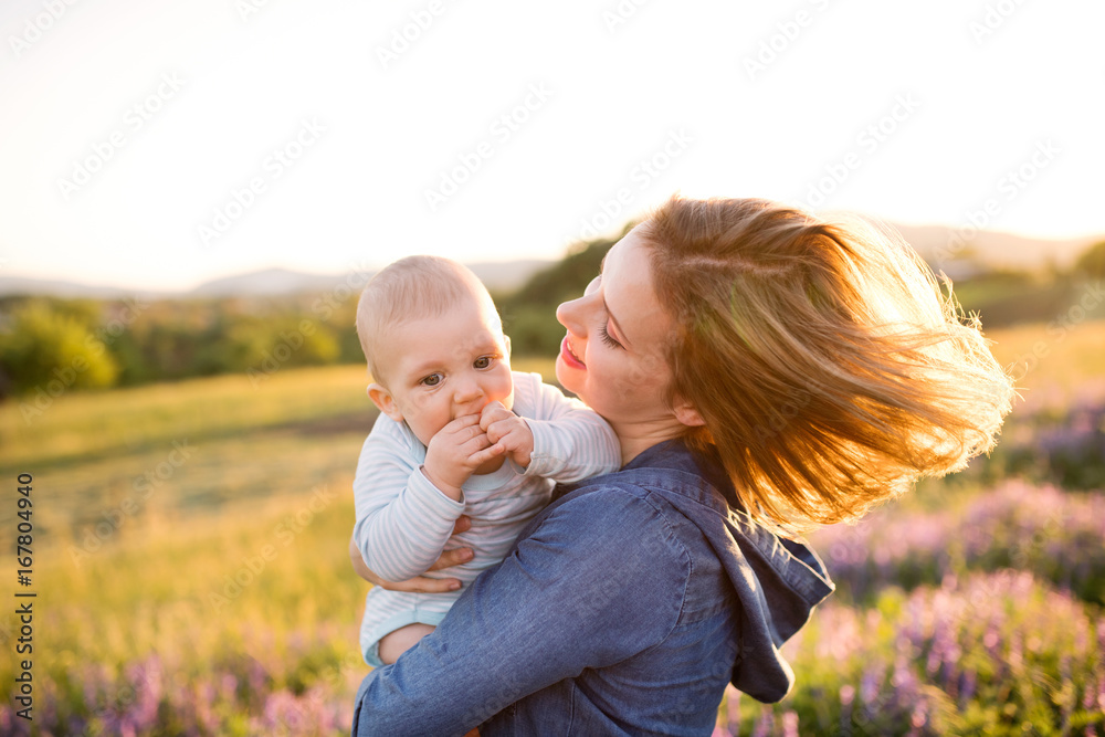 Young mother in nature with baby son in the arms.