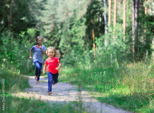 happy little girl and boy run play in summer nature