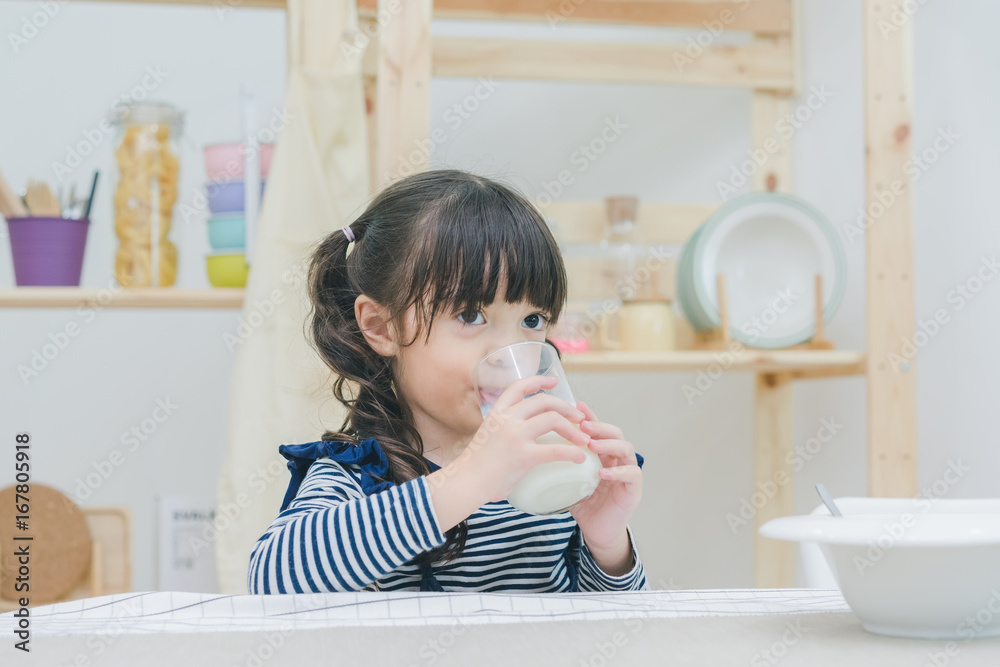 A little cute girl drinking milk after have a breakfast in the dinning room, healthy food A little cute girl drinking milk after have a breakfast in the dinning room, healthy food