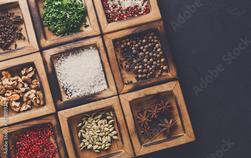 Diverse spices in a wooden boxes at black background © Prostock-studio