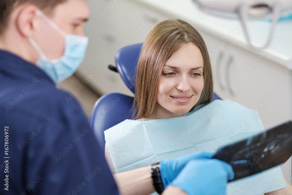 Fototapeta premium Doctor dentist man shows to patient girl x-ray
