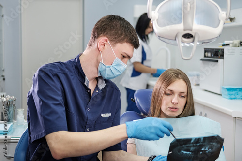 Doctor dentist man shows to patient girl x-ray