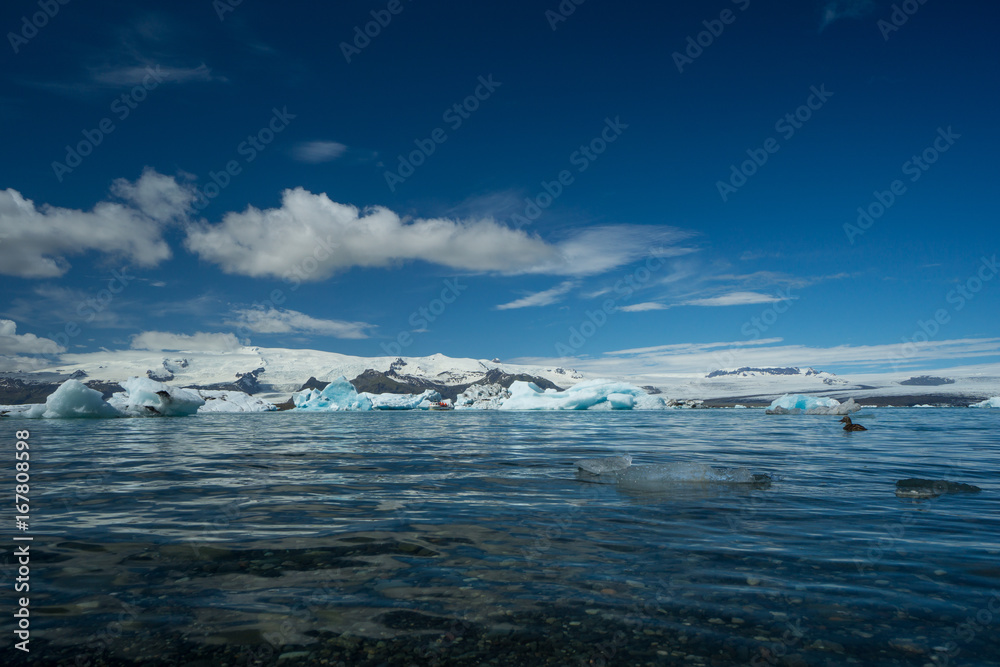 Obraz premium Iceland - Clear water of glacial lake with boat far between ice floes