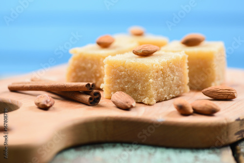 Halava, Indian flour sweetmeats cut in squares decorated with almonds on wooden board side view photo